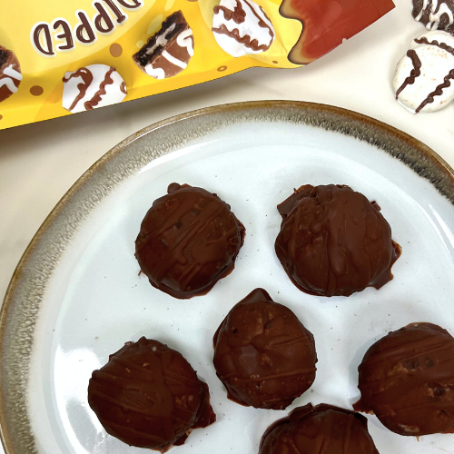 Chocolate-dipped cookies and cream truffles on a ceramic plate