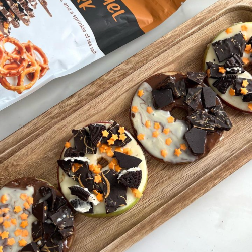 Chocolate-dipped apple slices topped with pretzel bark pieces, crushed cookies and orange star sprinkles