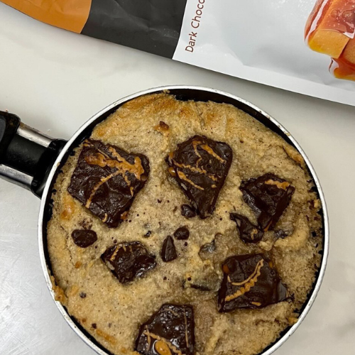 Warm skillet cookie topped with chunks of sea salt caramel pretzel bark