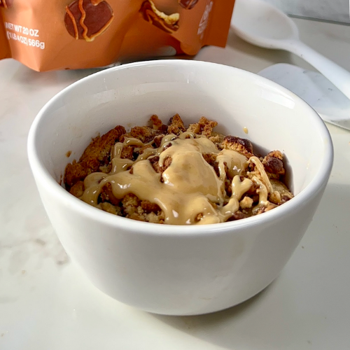 Single serve peanut butter chocolate cake in a white ramekin topped with crushed cookie bites and peanut butter drizzle
